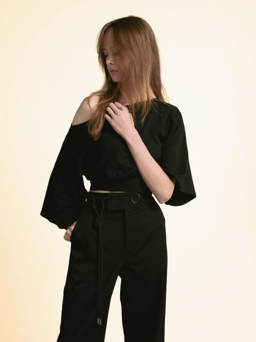Three-quarter view of the black ORY Kimo Off-Shoulder Top with wide-leg trousers